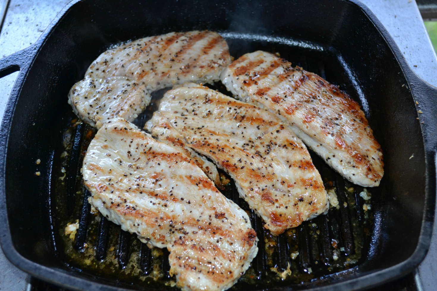 A healthy, colorful skillet dinner of fresh veggies, grilled turkey cutlets served on a cast iron skillet and drizzled with sweet chilli sauce.