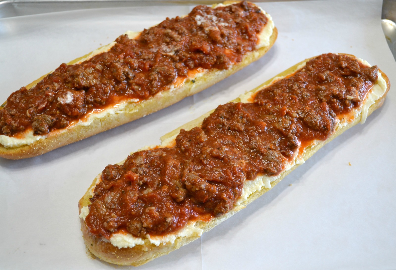 Loaves of garlic bread topped with a ricotta cheese layer, a meat sauce, and lots of melted mozzarella cheese. Perfect for dinner or cut into smaller pieces as an appetizer.
