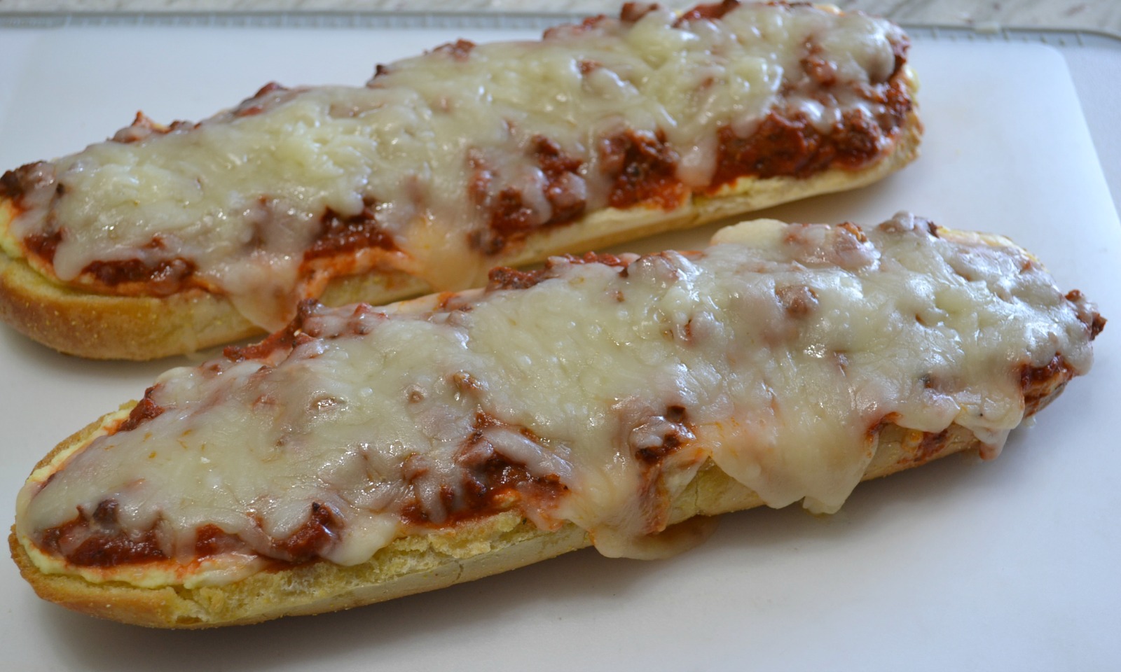 Loaves of garlic bread topped with a ricotta cheese layer, a meat sauce, and lots of melted mozzarella cheese. Perfect for dinner or cut into smaller pieces as an appetizer.