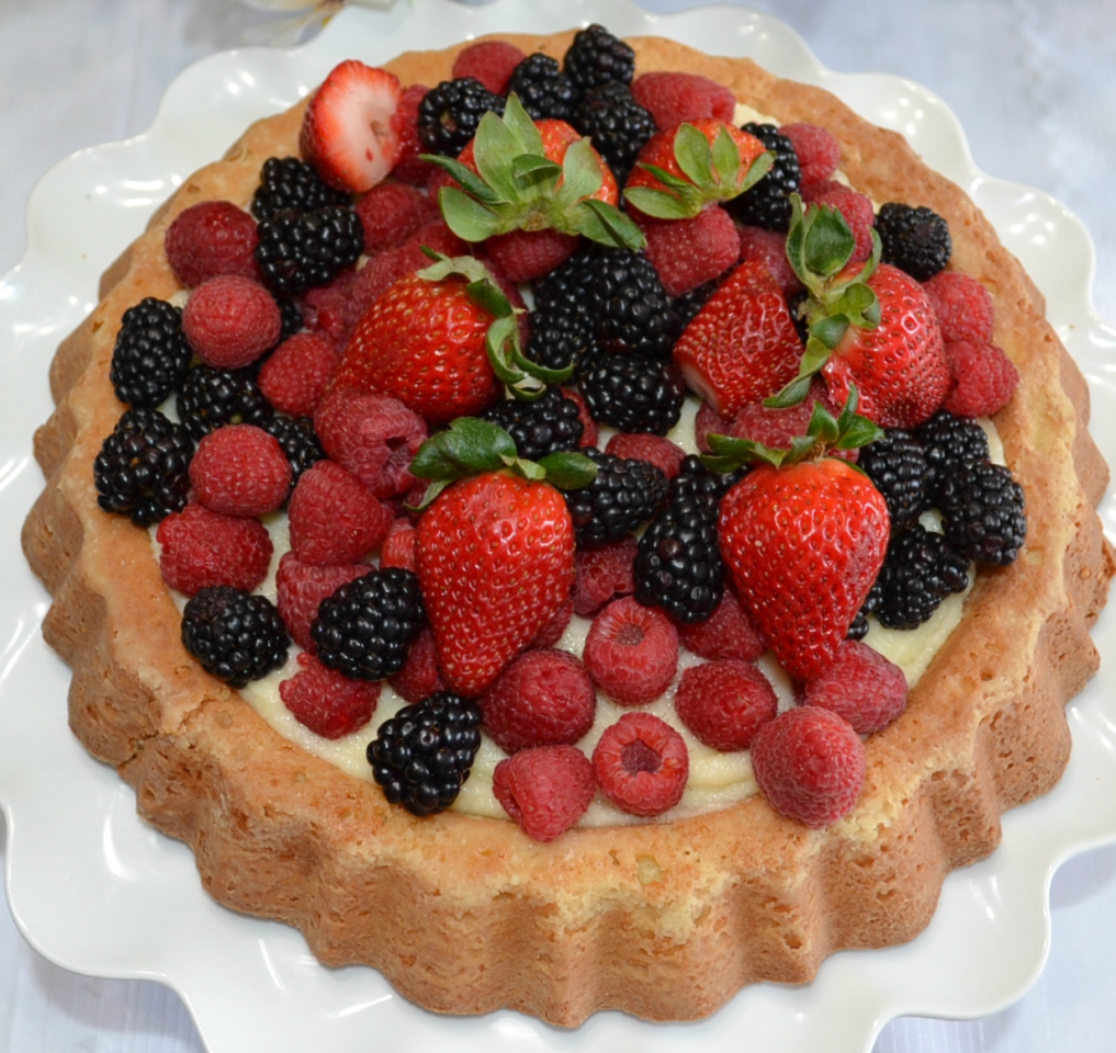 Raspberry Almond Tiara Cake is baked in a tiara pan, has almond paste in the cake, filled with a mascarpone layer and topped with fresh berries. Drizzle fresh raspberry sauce.