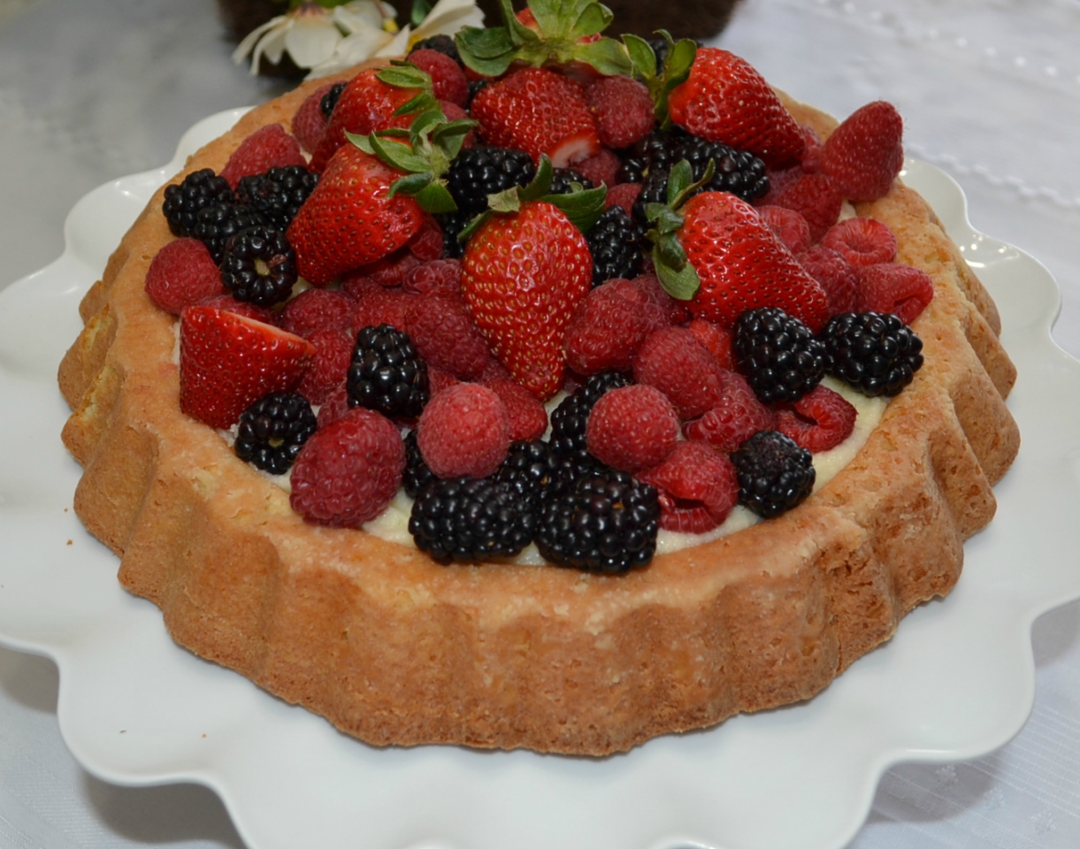 Raspberry Almond Tiara Cake is baked in a tiara pan, has almond paste in the cake, filled with a mascarpone layer and topped with fresh berries. Drizzle fresh raspberry sauce.