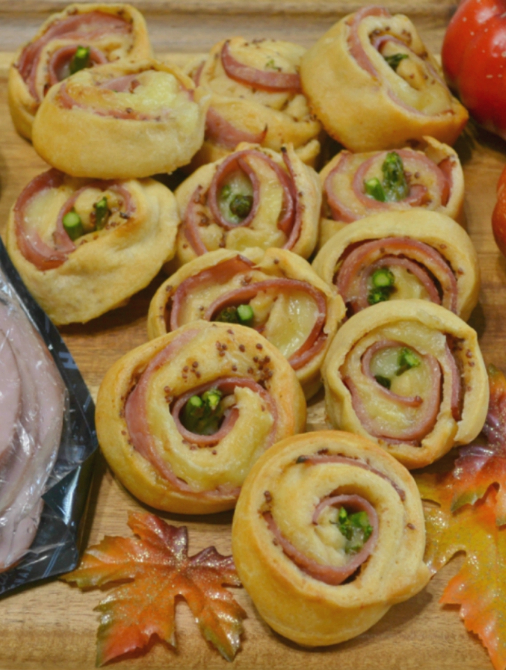 Ham-Brie-Asparagus Pinwheels are an easy appetizer with these ingredients baked in a crescent dough. They have a spread of honey mustard and warm, melted cheese. 
