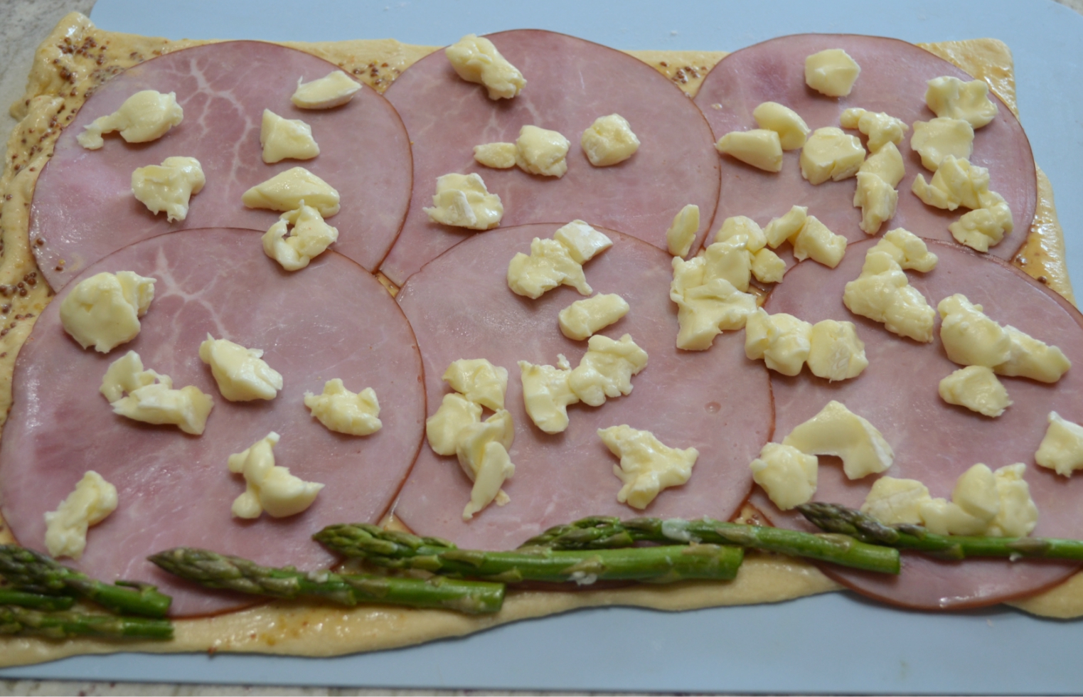 Ham-Brie-Asparagus Pinwheels are an easy appetizer with these ingredients baked in a crescent dough. They have a spread of honey mustard and warm, melted cheese.