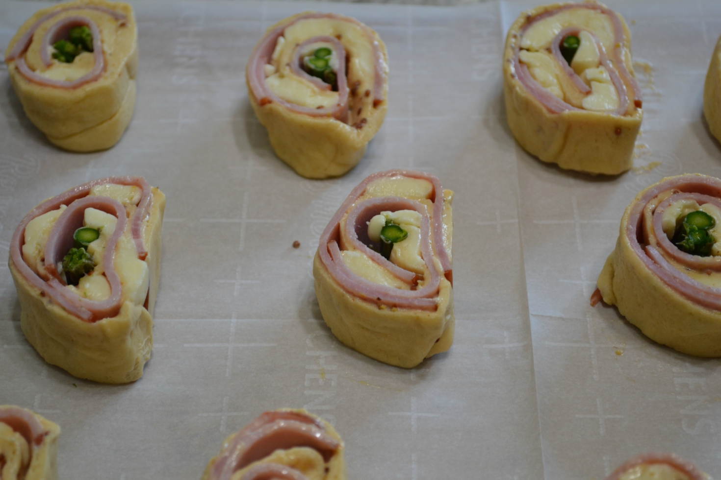 Ham-Brie-Asparagus Pinwheels are an easy appetizer with these ingredients baked in a crescent dough. They have a spread of honey mustard and warm, melted cheese.