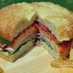 Picnic Foccacia Sandwich is loaded with meats, cheeses,and veggies. Made on a foccia loaf, drizzled with italian dressing and cut into beautiful wedges.