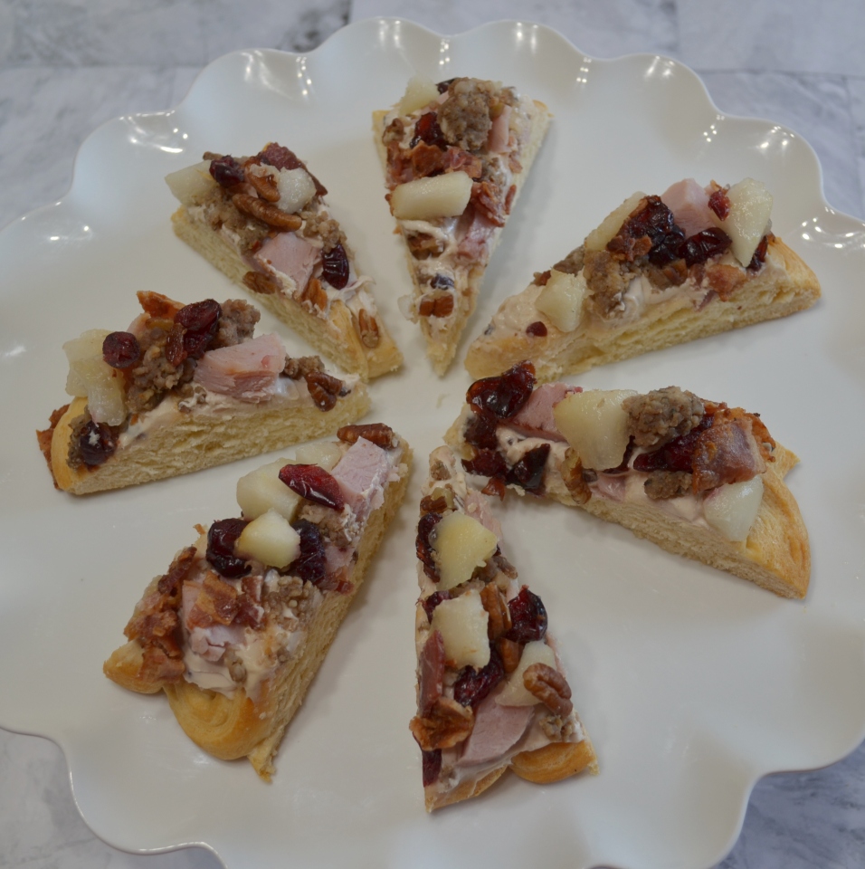 Holiday Pear Appetizer Wreath starts with a crescent crust,honey pecan cream cheese spread and topped with pears,ham,sausage,nuts,bacon,cranberries,and a drizzle of honey