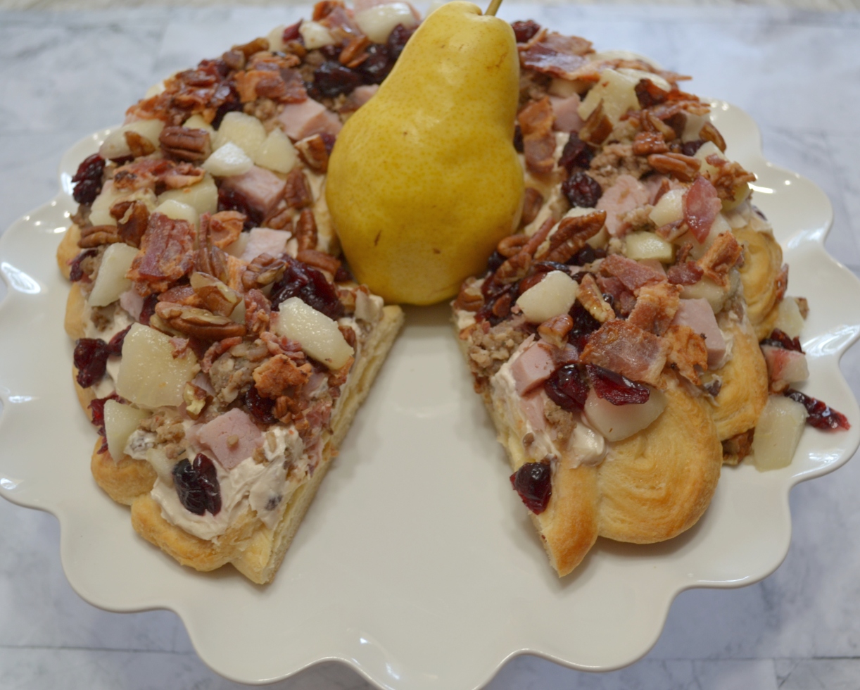 Holiday Pear Appetizer Wreath starts with a crescent crust,honey pecan cream cheese spread and topped with pears,ham,sausage,nuts,bacon,cranberries,and a drizzle of honey