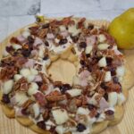 Holiday Pear Appetizer Wreath starts with a crescent crust,honey pecan cream cheese spread and topped with pears,ham,sausage,nuts,bacon,cranberries,and a drizzle of honey.