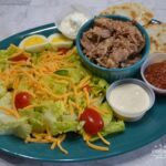 BBQ Pulled Pork Salad is a slow cooked,tender pork butt with sauce served on a bed of lettuce,veggies,cheese and topped with ranch dressing.