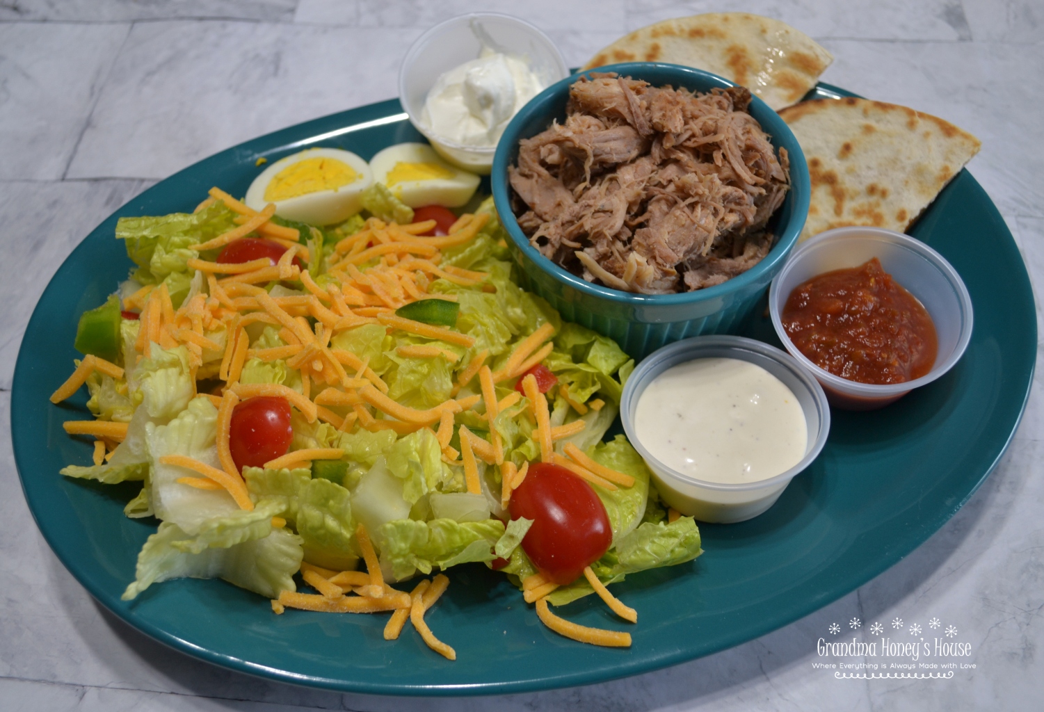 BBQ Pulled Pork Salad is a slow cooked,tender pork butt with sauce served on a bed of lettuce,veggies,cheese and topped with ranch dressing. 