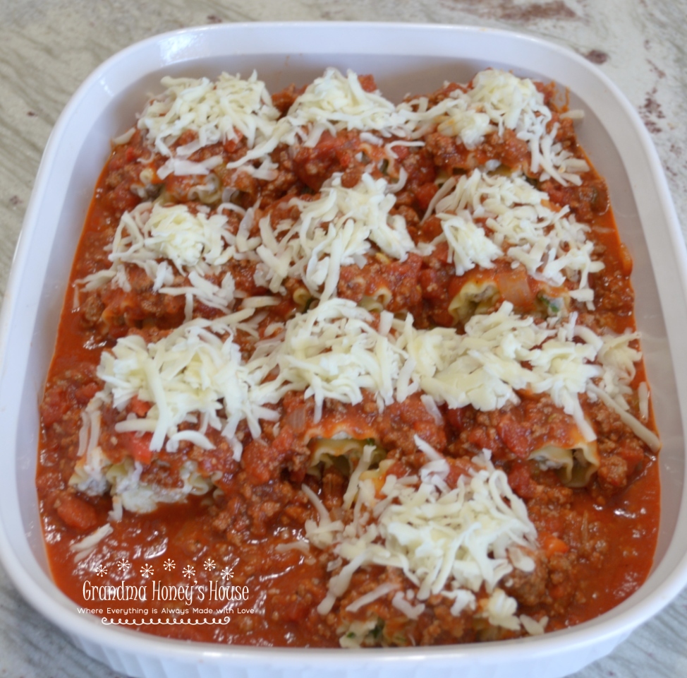 Photo of Sausage Spinach Lasagna Roll-Ups in a white baking dish before baking.