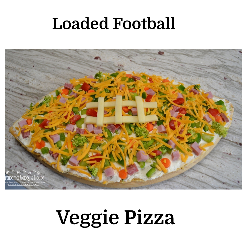 Loaded football veggie pizza is a crescent crust in a football shape, covered with cream cheese filling, veggies, meat and cheese. The perfect appetizer.