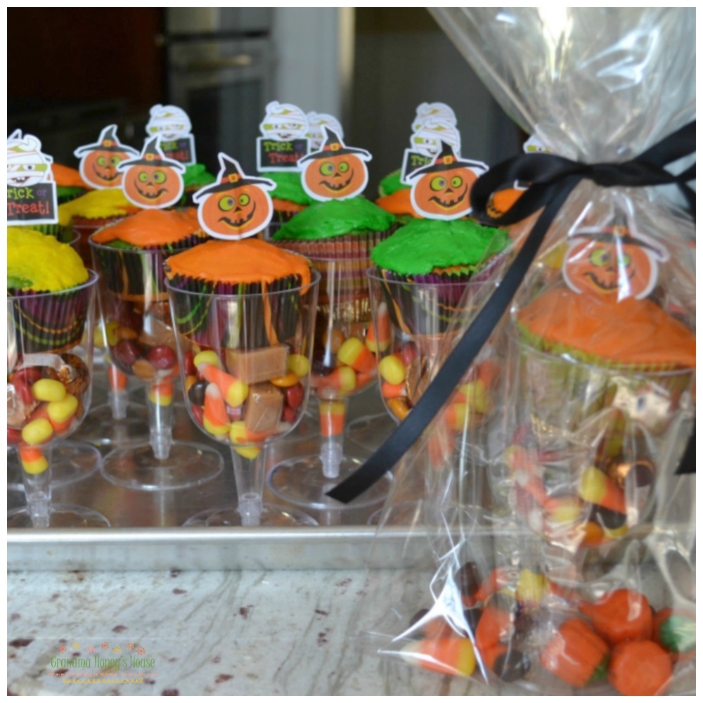 Halloween Treat Bags for tick-or-treat, or any party favor. Individual glasses filled with Halloween candy and a cupcake, then wrapped in a cellophane bag with a bow. 