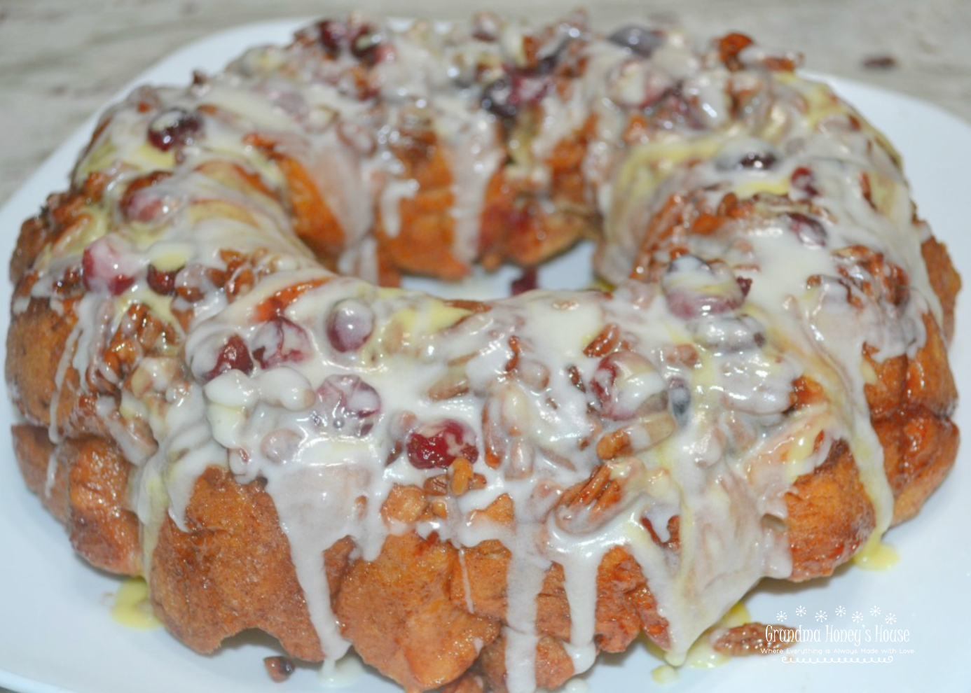 Cranberry Orange Cinnamon Monkey Bread  is a baked monkey bread made from cinnamon rolls and orange rolls with icing drizzled on it and topped with cranberries and pecans.