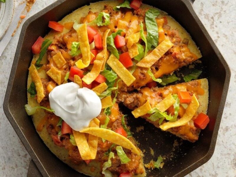 Taco Skillet Pizza is a cornbread crust filled with mexican themed ingredients.