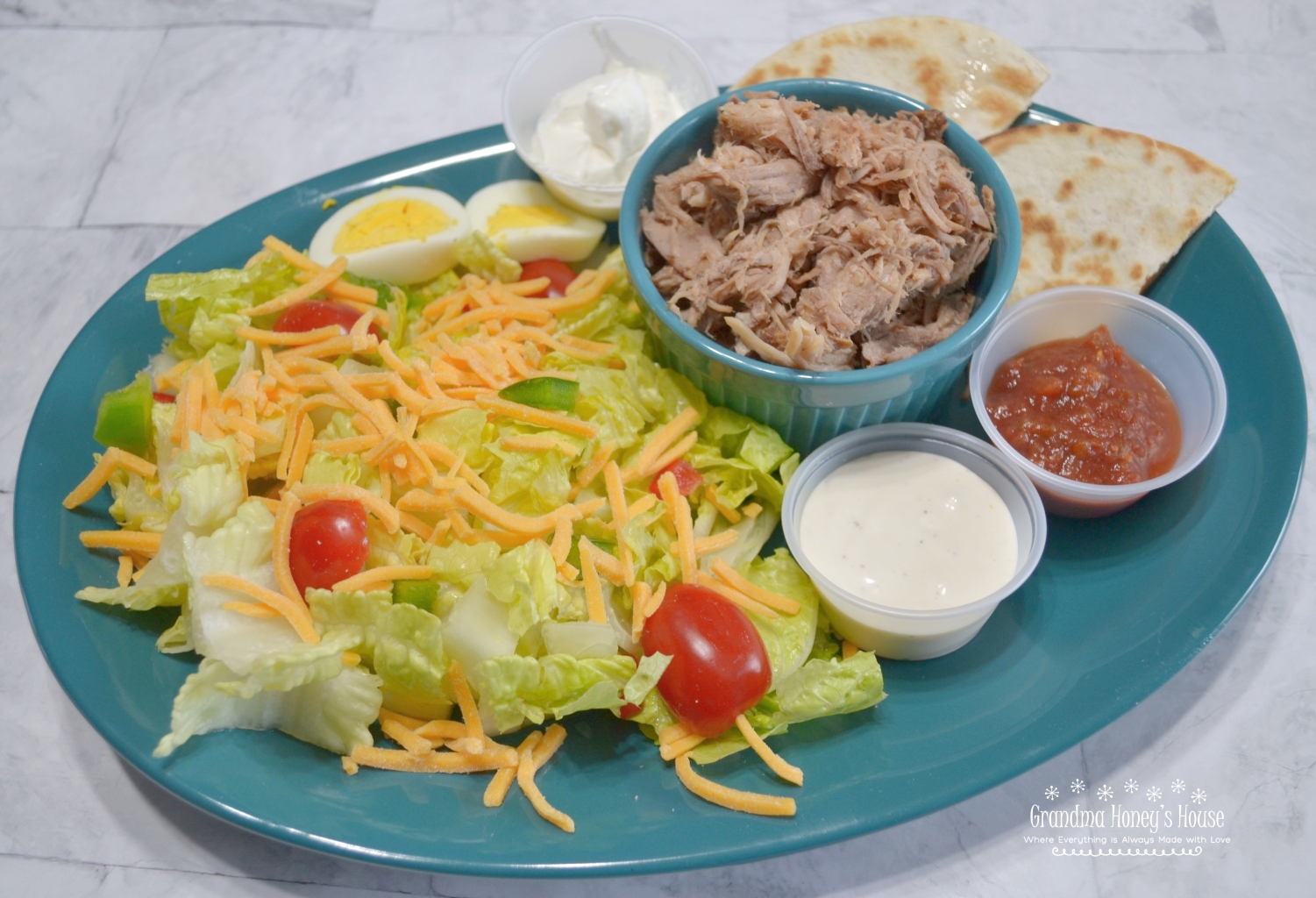 BBQ Pulled Pork Salad is a slow cooked,tender pork butt with sauce served on a bed of lettuce,veggies,cheese and topped with ranch dressing. 