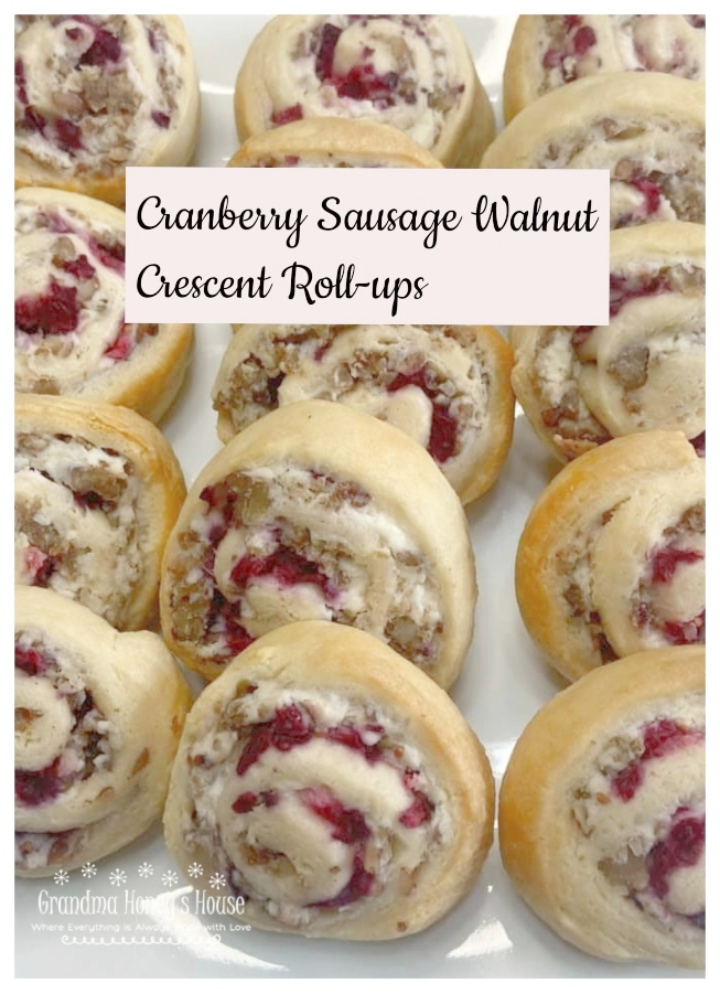 A crescent dough sheet filled with a mixture of cream cheese, cooked sausage crumbles, walnuts, topped with cranberry sauce, then rolled, sliced and baked.