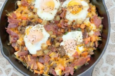 Hearty Grilled Breakfast Skillet, a skillet full of meats, potatoes, veggies, eggs and cheese cooked on the grill in a cast iron skillet.