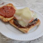 Pizza Burgers are seasoned ground beef patties, layered with mozzarella cheese, pepperoni, veggies, and topped with spoonfuls of warm pizza sauce. Serve on a garlic butter toasted bun.