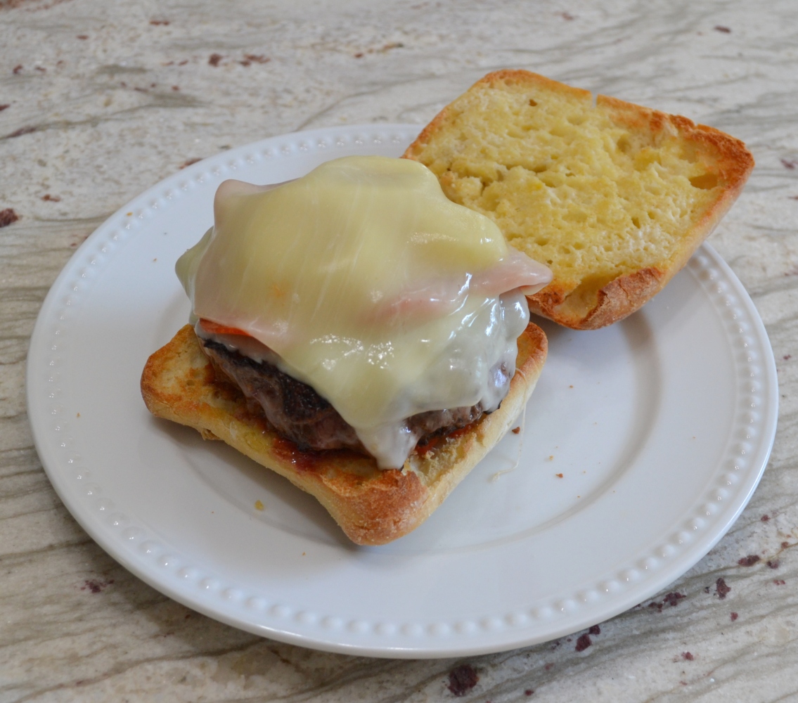 Pizza Burgers are seasoned ground beef patties, layered with mozzarella cheese, pepperoni, veggies, and topped with spoonfuls of warm pizza sauce. Serve on a garlic butter toasted bun.