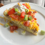 Southwest Breakfast Tart is packed with sausage, peppers, green chiles, cheese, eggs, and baked in a pie crust. It is served with toppings of salsa, sour cream, green onions and diced tomatoes.  