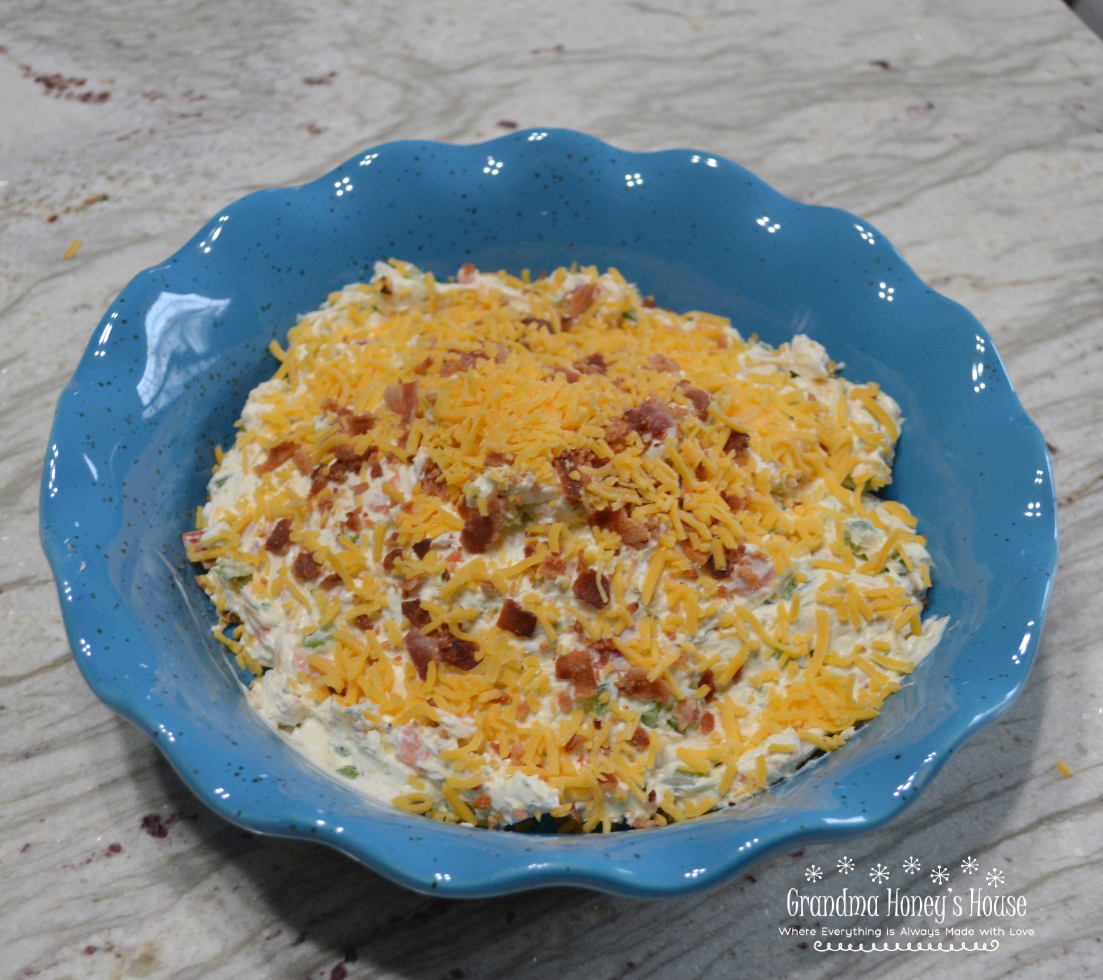 Vegetable Pizza Dip with bacon is a creamy dip made with cream cheese, sour cream, mayo, a Ranch dressing packet, a mixture of veggies, cheese and bacon.  It is served cold with a variety  of breads, crackers, chips, and celery sticks